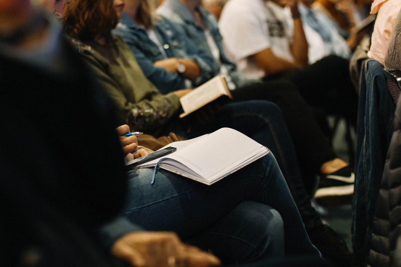 People taking notes and reading Scripture at a missions gathering